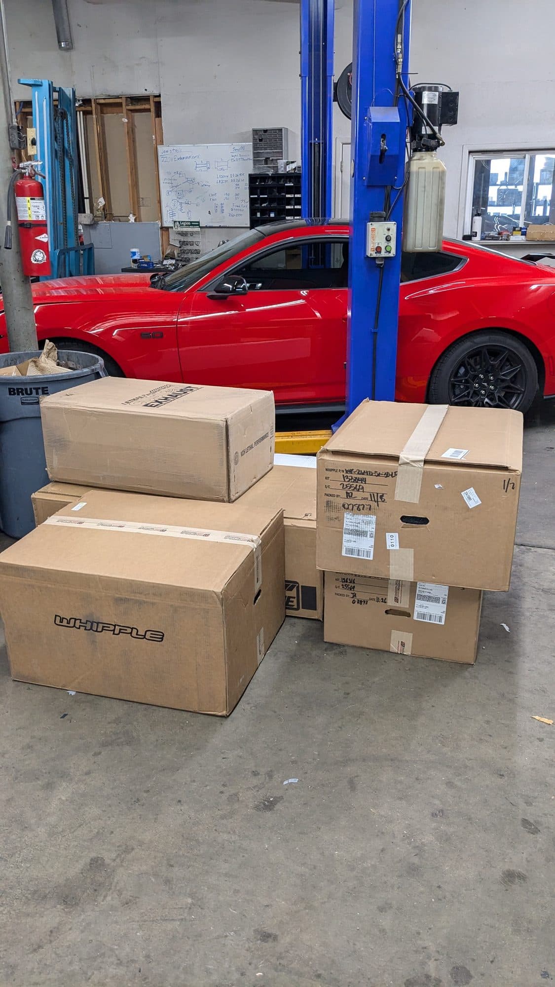 Boxes of customer-supplied parts stacked next to a car on the lift at Turbo Lab in Orem, UT