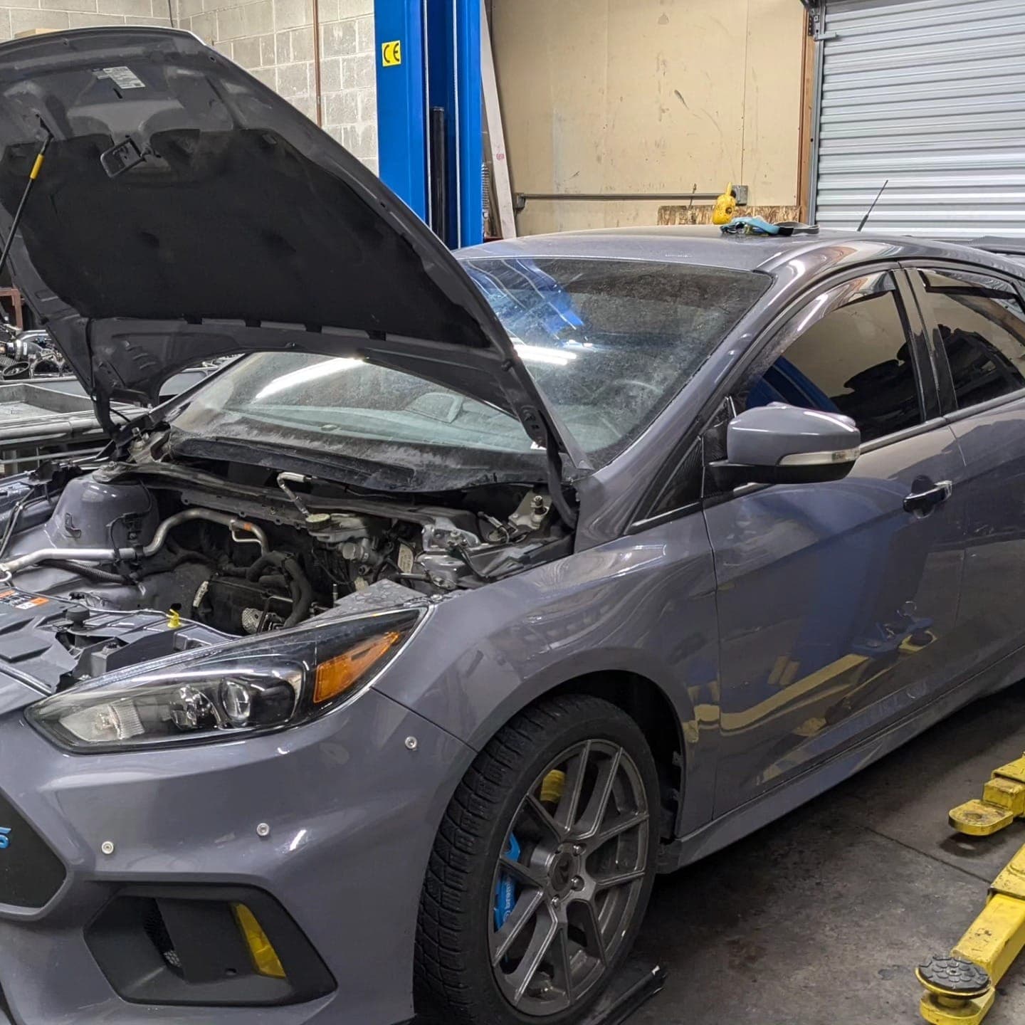 Ford Focus RS with the hood up on a lift after its engine was pulled for inspection at Turbo Lab