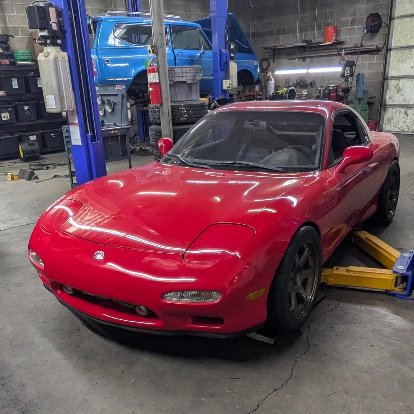 Red Mazda RX-7 FD on a lift for custom AC lines at Turbo Lab in Orem, UT