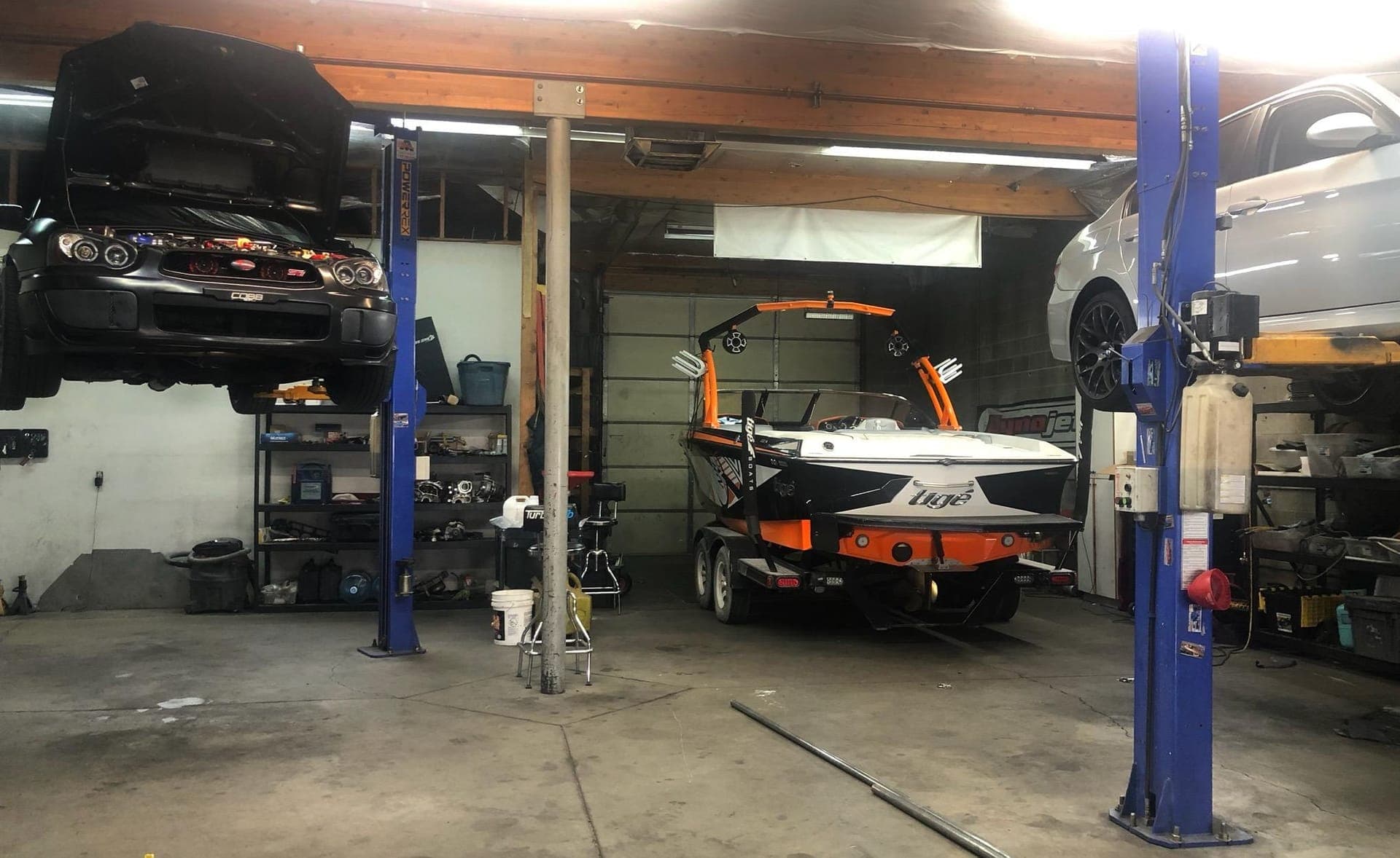 Inside Turbo Lab's shop in Orem: a Subaru STI on a lift, a wakeboat in the bay, and a Dynojet banner