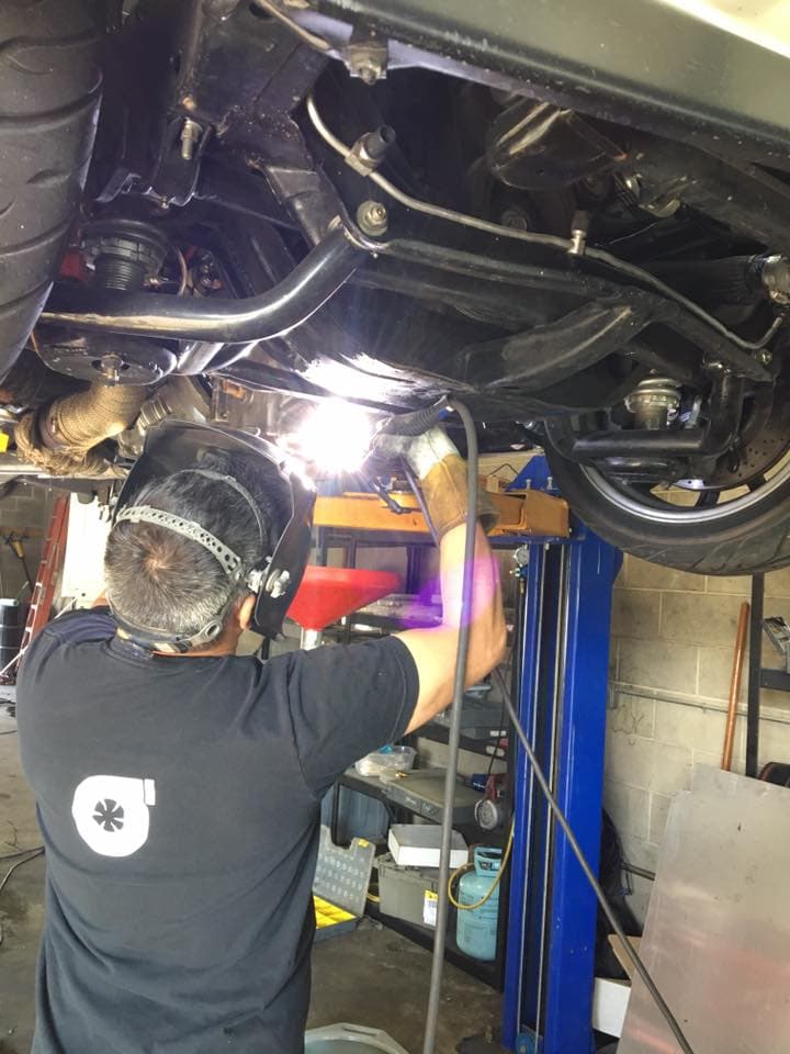 Turbo Lab tech welding under a car on the lift in Orem, UT