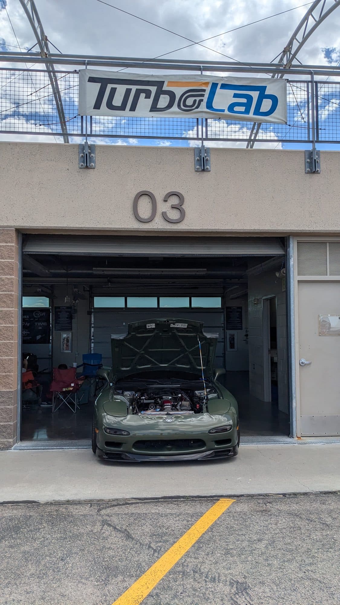 Green Mazda RX-7 in a pit garage at the track