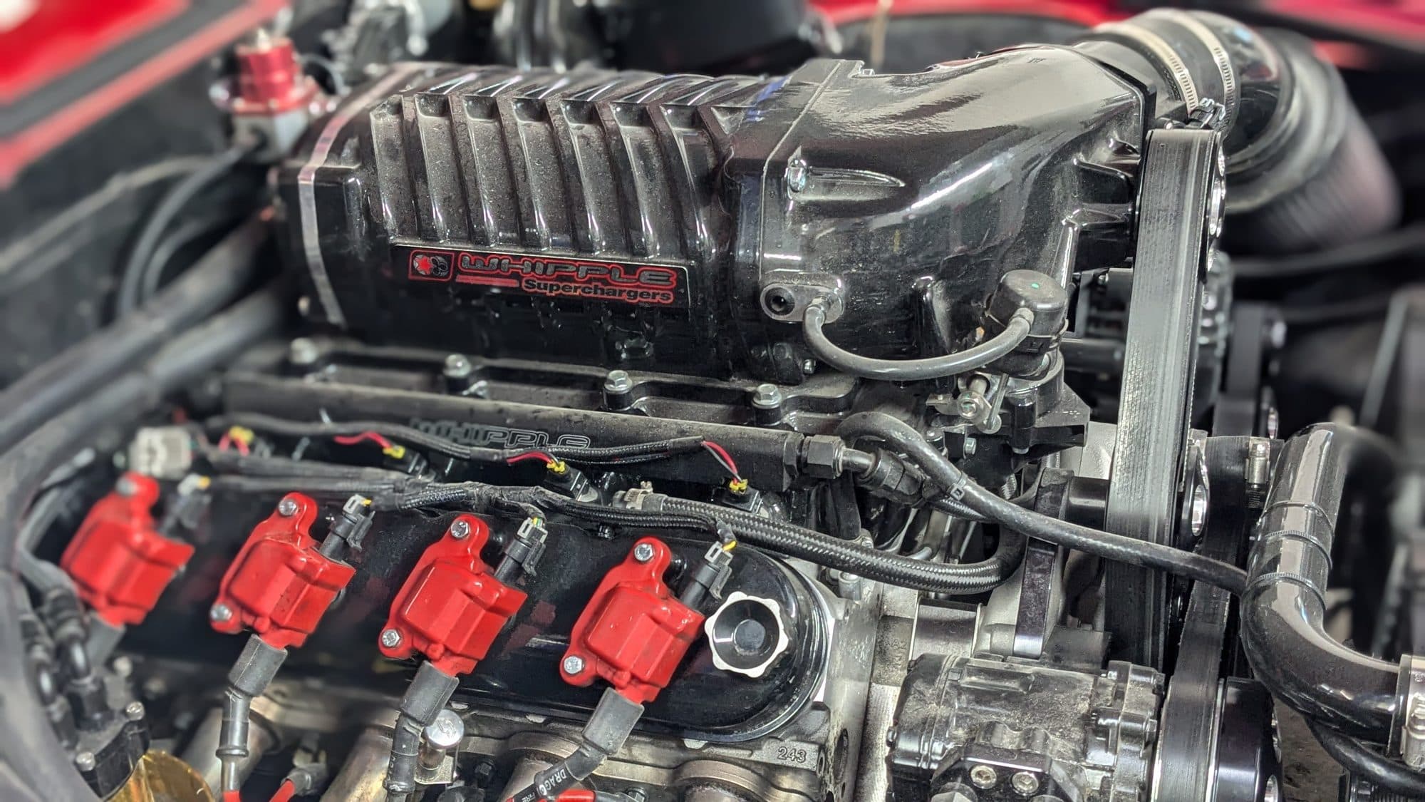 Supercharger installed on a V8 with red coil packs at Turbo Lab in Orem, UT